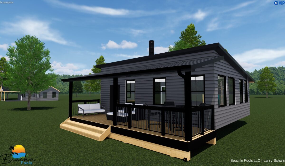 Modern gray house with black trim and large windows on a wooden deck, surrounded by green lawn and trees under a blue sky.