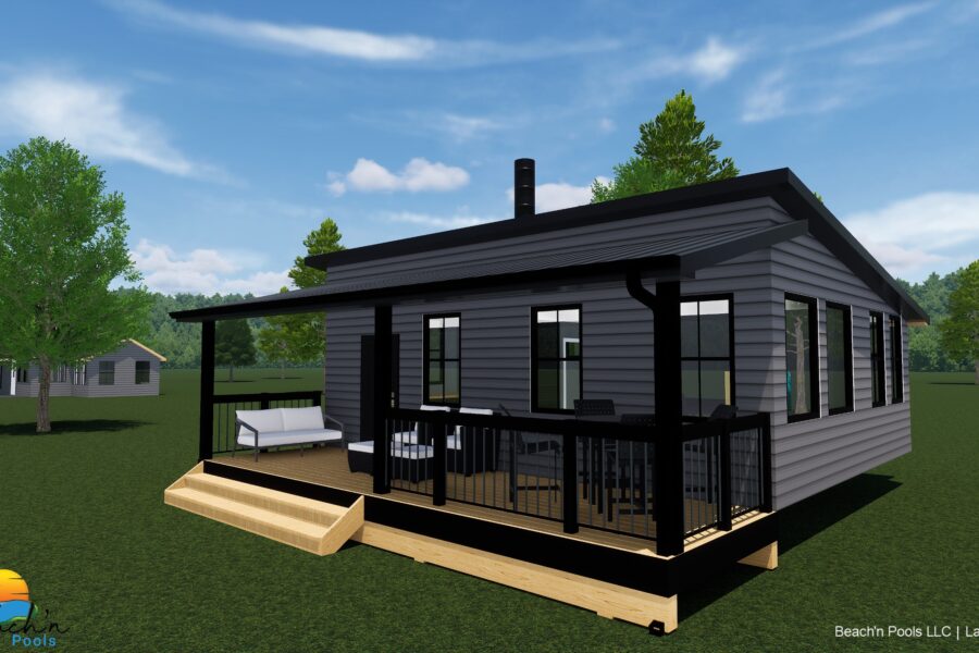 Modern gray house with black trim and large windows on a wooden deck, surrounded by green lawn and trees under a blue sky.